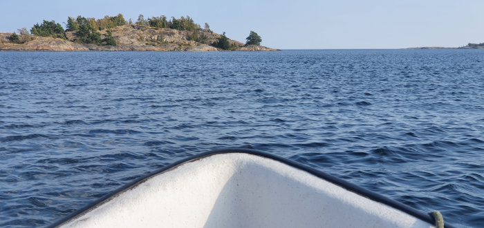 Vy över havet från en båt med skärgårdsöar i bakgrunden under en klar dag.