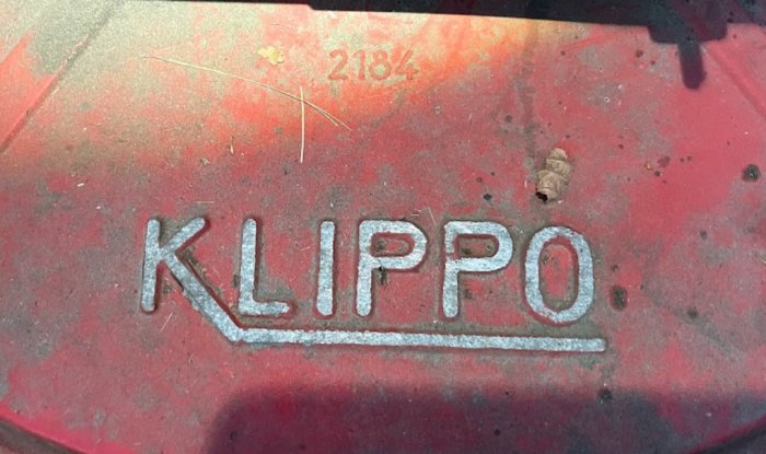 Närbild på en röd Klippo gräsklipparhölje med tydligt Klippo-logotyp och smuts.