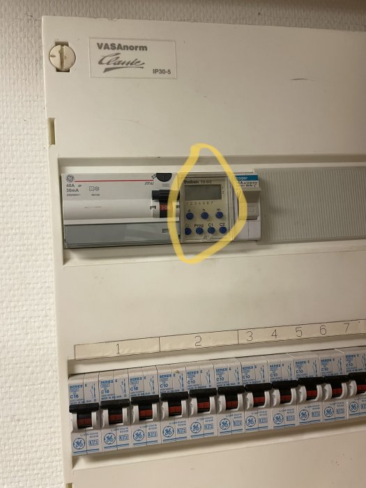 Elcentral med säkringar och en digital timer med blå knappar; displayen verkar trasig.