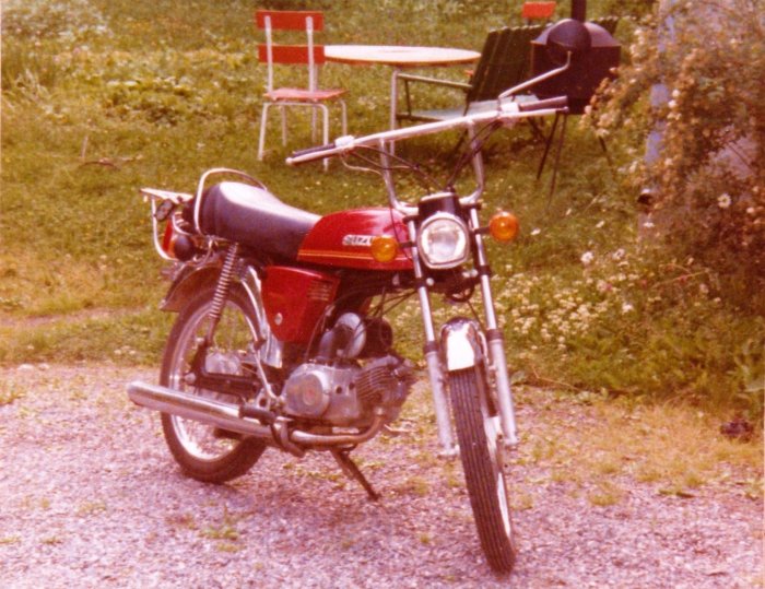 En röd Suzuki K50 motorcykel från 1978 med buffalostyre parkerad utomhus.