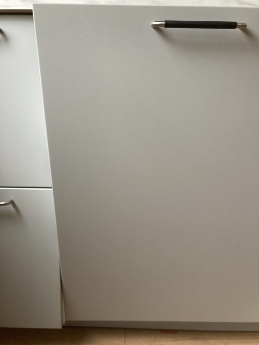Diskmaskinsfront som tar i köksstomme, synlig friktionsskada på nedre delen av luckan.