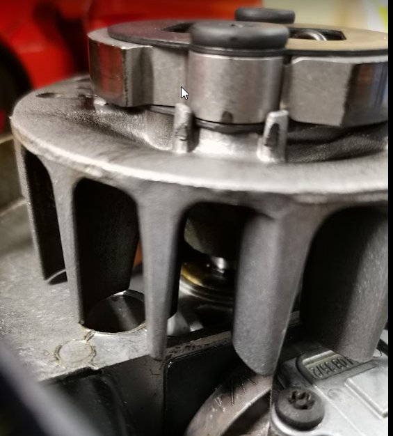 Närbild på en frilagd motor med fokus på en komponent och två synliga skruvar.