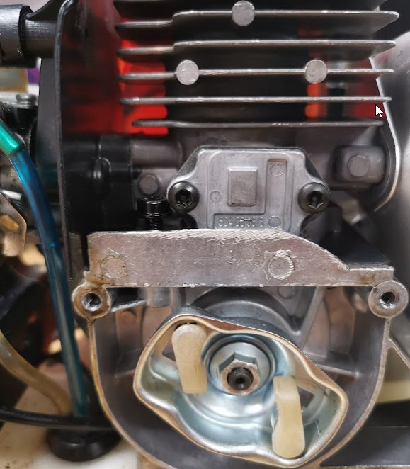 Öppen motor med synligt inre, fokus på en komponent med två skruvar och en fjäder, eventuell referens till kilekontroll.