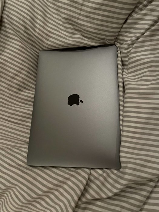 Stängd MacBook Air M1 ligger på ett randigt lakan.