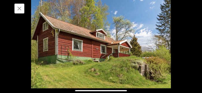 Rött trähus med grönt tak och omgivning som visar början på grävarbeten.