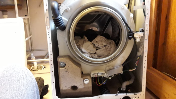Frontpanelen avmonterad på tvättmaskin som visar trumman och interna komponenter.