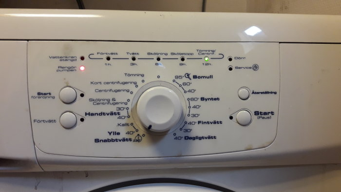 Kontrollpanel på en tvättmaskin med olika programval och funktioner, fokus på inställningsratten.