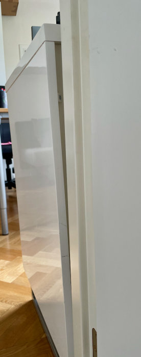 Lutning synlig på en vit bänk bredvid en dörrkarm, som indikerar en svacka i golvet.