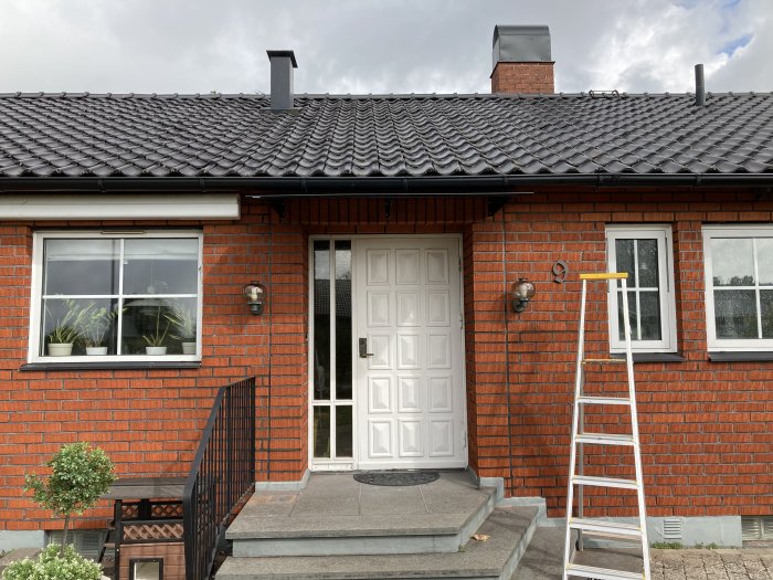 Nymonterat svart tegelpannetak på en tegelvilla, en stege står intill huset.