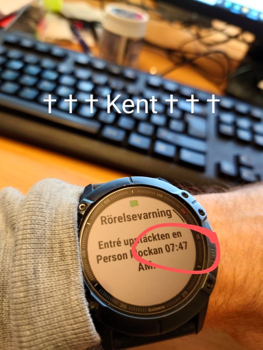 Smartklocka på handled visar rörelselarm om person upptäckt på en plats klockan 07:47.