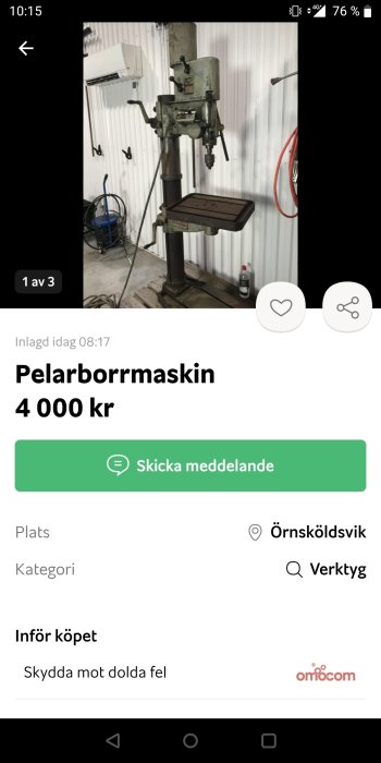 Begagnad pelarborrmaskin i en verkstadsmiljö med vit bakgrund och verktyg på väggen.