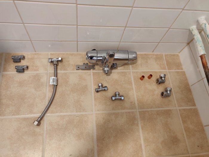 VVS-material upplagt på kakel, inkl. blandare, flexslang och olika anslutningsrör.