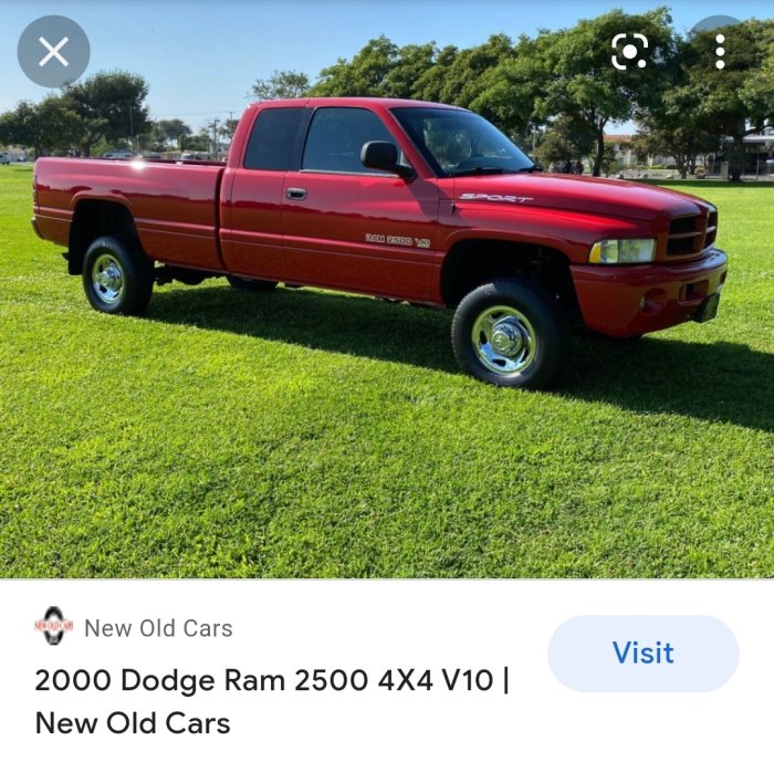 Röd 2000 Dodge Ram 2500 Sport 4x4 pickup parkerad på grönt gräs.