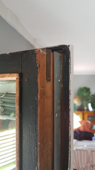 Close-up of a door frame with poorly painted edges and visible wood under scraped paint.