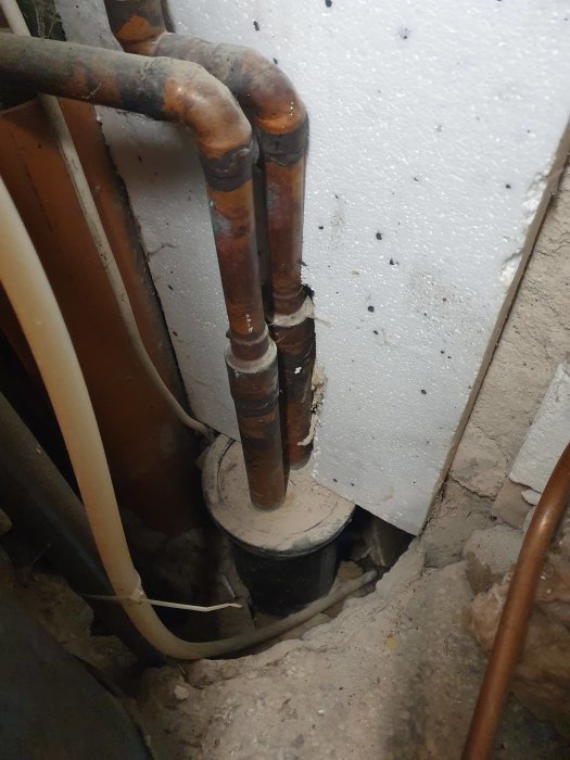 Kopparrör som böjer 90 grader vid genomföring genom betonggolv, potentiell läckplats.