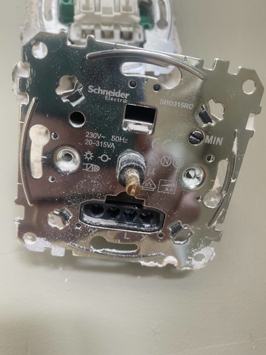 Öppen Schneider Electric dimmer installerad på vägg med synliga ledningar och justerskruv för minimilast.