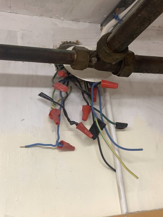 Oorganiserad samling av elektriska kablar och säkringar på en vägg.
