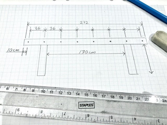 Handritad skiss av bord ritad på millimeterpapper med måttangivelser och blyertspenna.