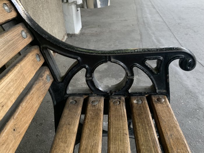 Närbild på en parkbänk med träslats och gjutjärnsstöd, symboliserar en paus i nedförsbacke.