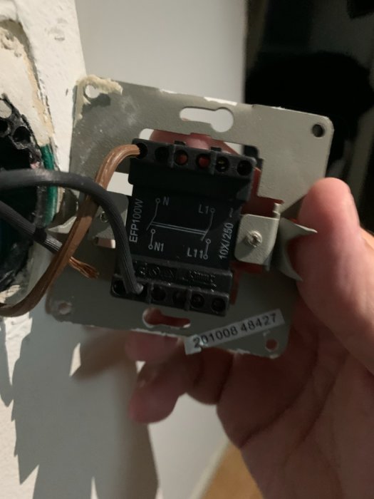 Hand håller en ny strömbrytare från Biltema med ledningar och märkning L1, L2, L3.