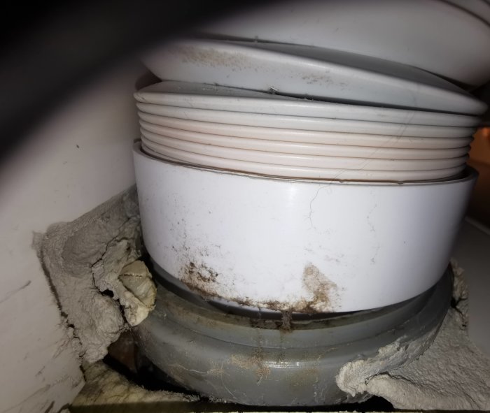 Närbild på ett smutsigt avloppsrör med isolering som ser skadad ut där det kan dra.