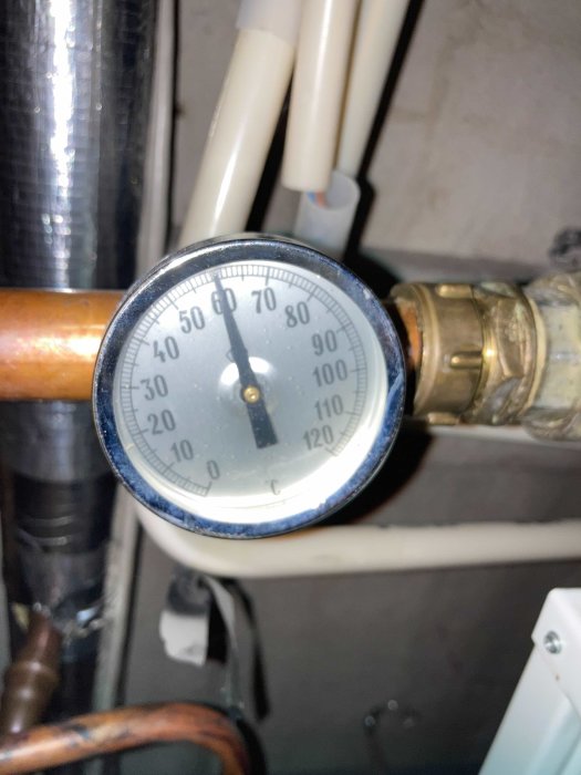 Termometer som visar cirka 65 grader, ansluten till rörsystem, indikerar överhettning av vatten i elpanna.