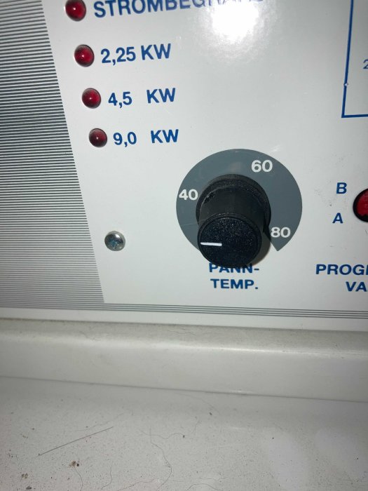 En närbild av en elpannas reglage med inställningsknapp för temperatur och strömstyrka indikatorer.