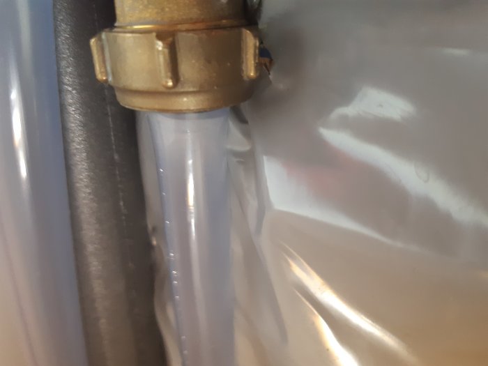 Transparent PVC-slang ansluten till säkerhetsventil vid varmvattenberedare.