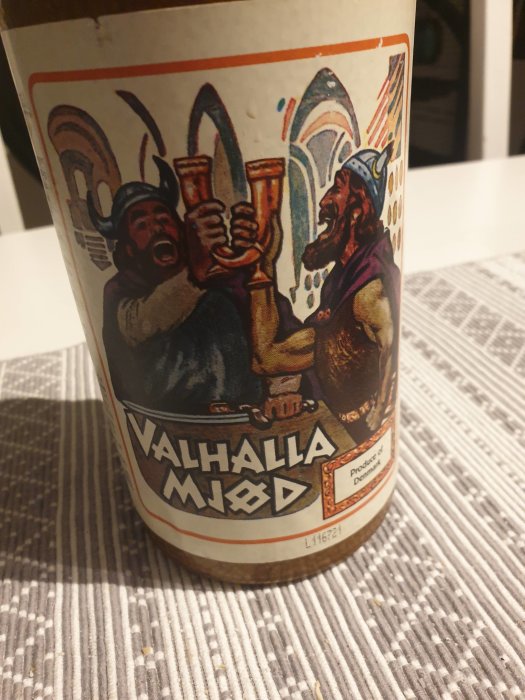 Etikett på en Valhalla Mjöd-flaska med tecknad bild av två vikingar som skålar.