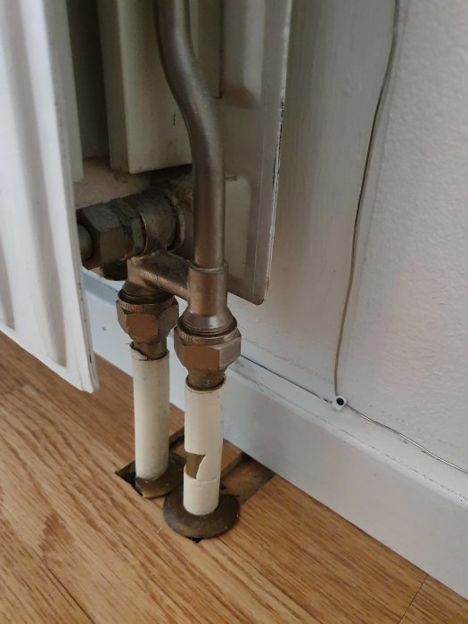 Äldre radiatorkoppling med synliga rör och isolering vid en vägg, möjlig anpassning för nytt vattenburet element diskuteras.