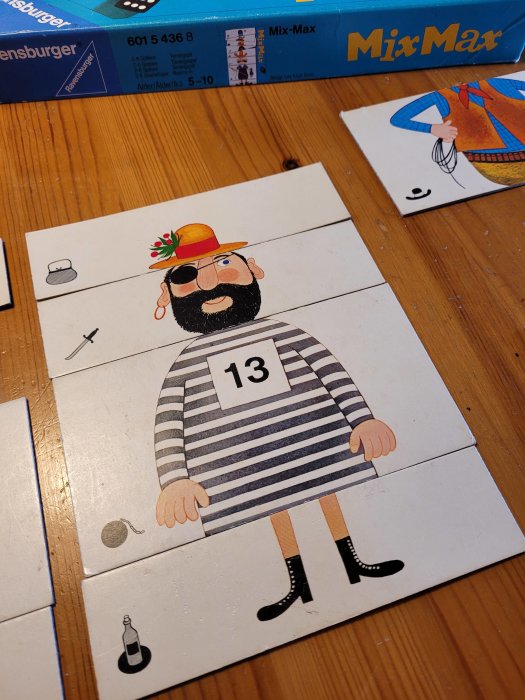 Illustration av pusselbit med tecknad fånge i randig tröja med nummer 13 och färgglad hatt på träbord.