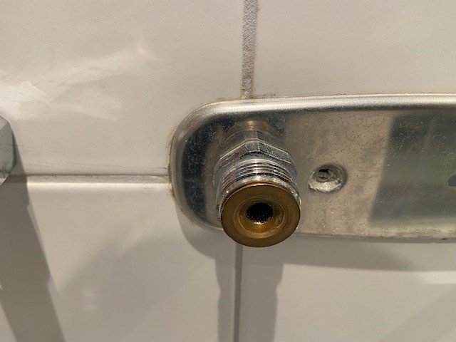 Ett väggmonterat blandarfäste i metallist med synbart rör och anslutning, inte pexkoppling.