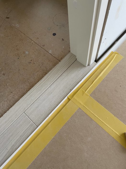 Tröskel som inte är helt fast monterad mot ett flytande laminatgolv vid en dörröppning.
