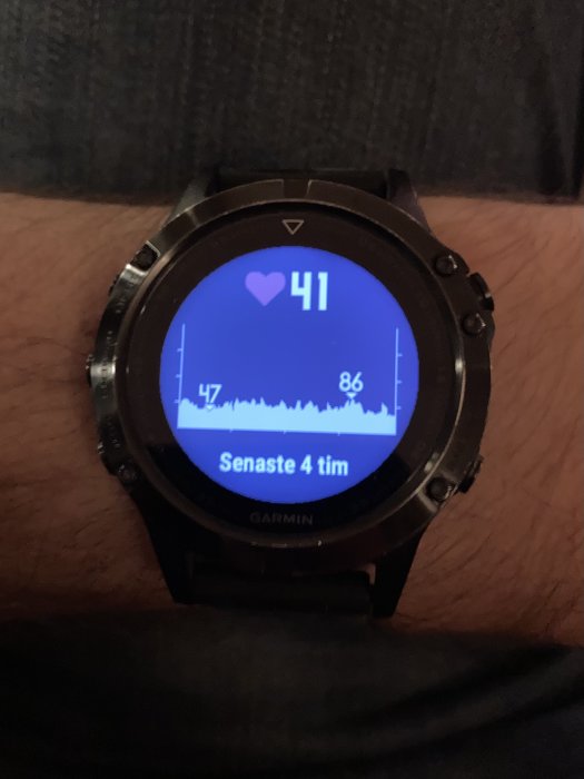 En smartklocka på ett handled som visar hjärtfrekvensdata över de senaste fyra timmarna.