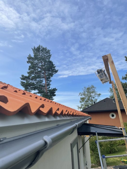 Uppdaterad hängränna monterad högre upp på taket med hus och himmel i bakgrunden.