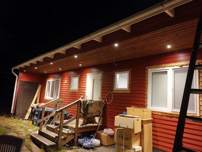 Nyligen installerade dimbara LED-spotlights under takutsprånget på ett rött hus i kvällsbelysning.