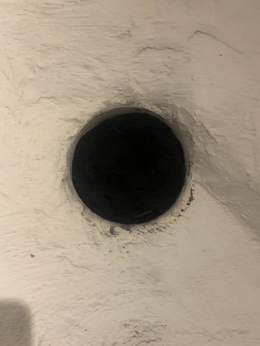 138 mm brett hål i en bullig vitmålad vägg efter borttagen kamin, redo för frånluftsventil.