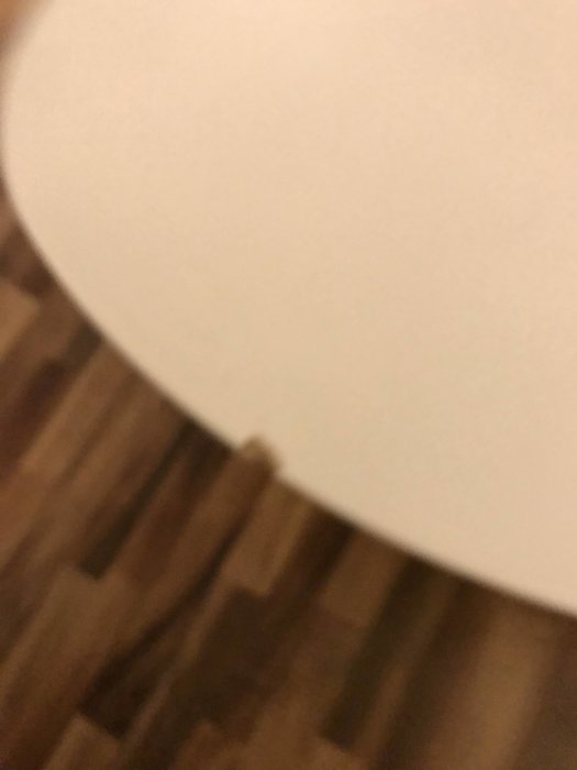 Otydlig närbild på en vit yta med suddig bakgrund av ett trägolv.