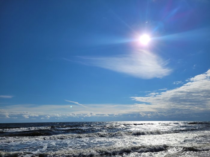 Solig dag vid havet med blå himmel och ljusa vågor.