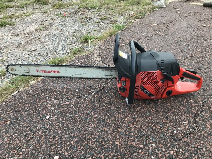 En Jonsered 2186 motorsåg med 28 tums svärd och uppgraderad cylinder och kolv ligger på en grusig mark.