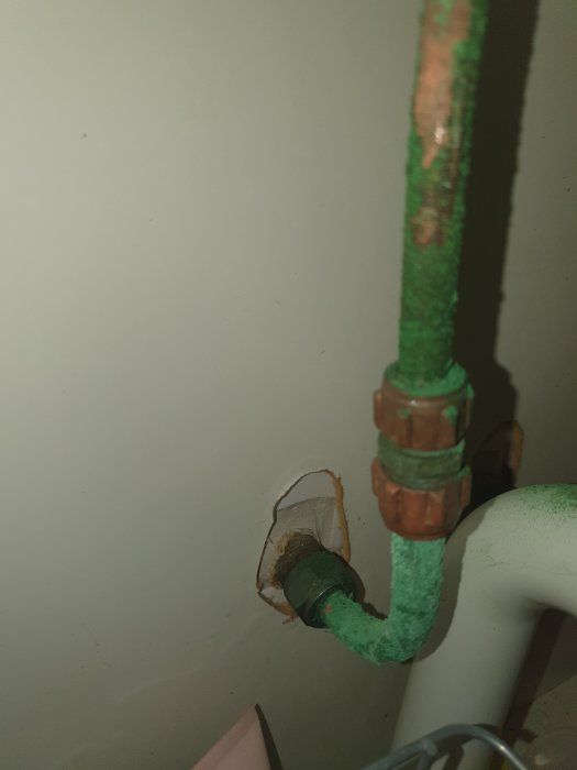 Ärgade vattenrör och beslag i en badrumsmiljö som behöver underhåll.