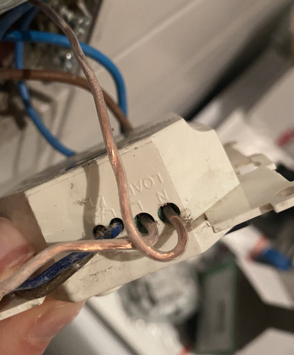 Elektriska kablar anslutna till en befintlig termostat med märkningarna L och N indikerande fas och nolla.