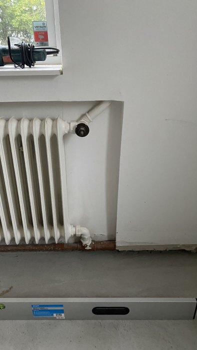 Vattenburen radiator kopplad till ett rör i ett rum, med avstängd ventil och elementskydd.