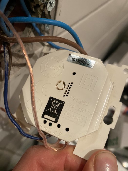 Baksidan av en elektrisk väggströmbrytare med trådar anslutna och modellinformation synlig.