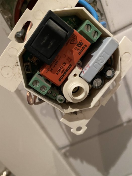 Baksida av en elektrisk anordning med kablar och komponenter synlig vid installation.