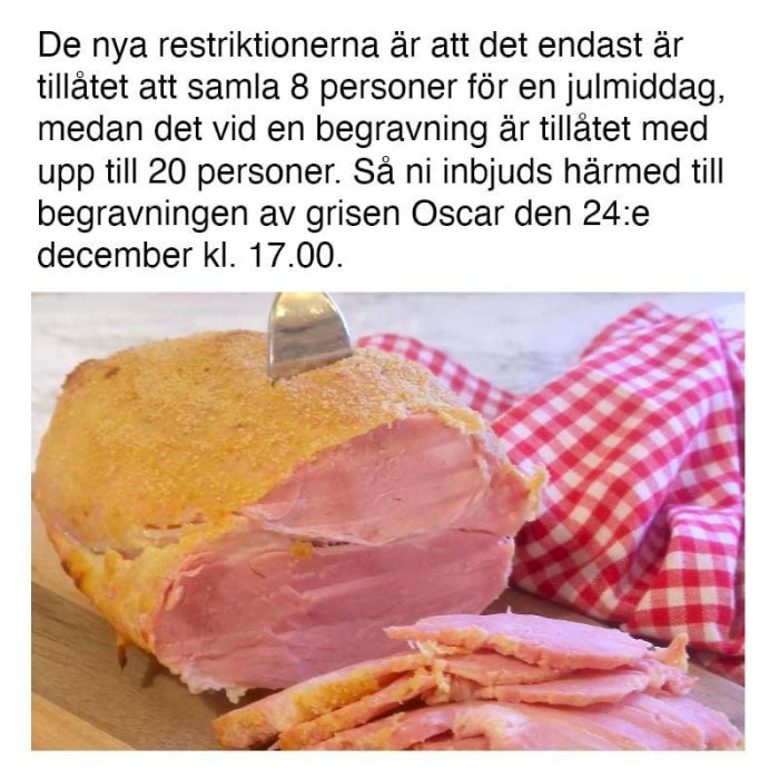 Halvskuren julskinka på skärbräda med rödvit rutig duk i bakgrunden.