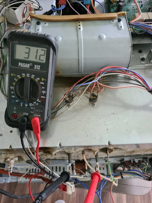 Multimeter mäter 3.12 volt på öppen elektronisk enhet, ingen jordkontakt synlig.