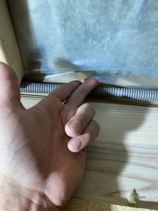 Hand som pekar på en otillfredsställande slut på en ångspärr som inte når golvet på en vind.