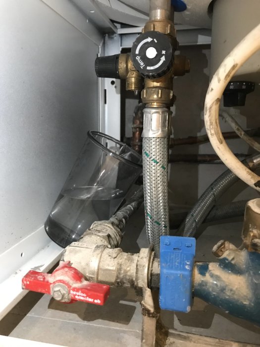VVS-installation med en Nibe Compac, rör, ventiler och en transparent bunke som samlar upp vatten under utrustningen.
