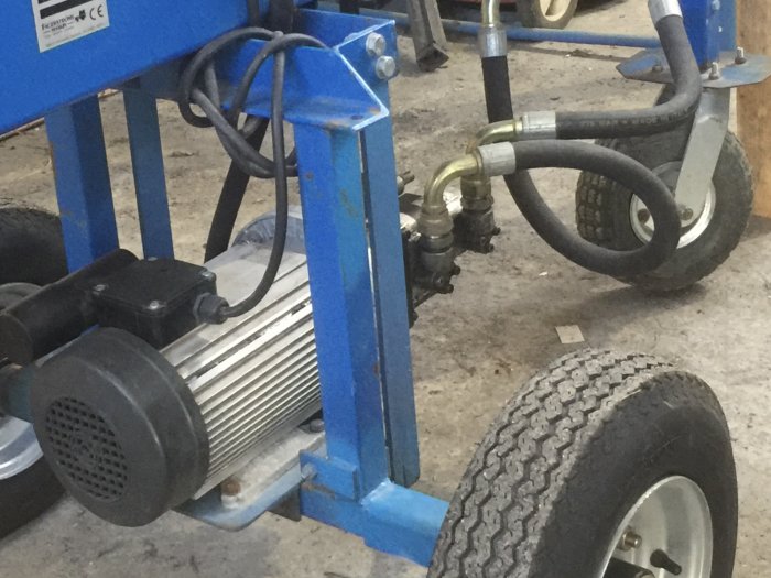 Närbild av en blå "Vimmerbyklyv" vedklyv med 1-faset motor och slangkopplingar.